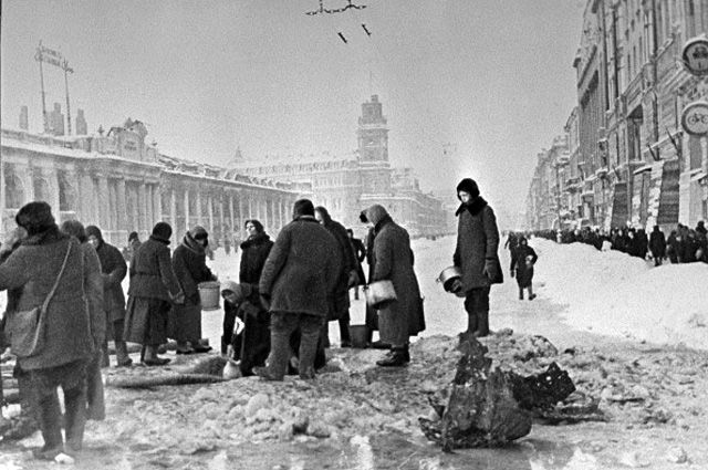 Жители блокадного Ленинграда набирают воду, появившуюся после артобстрела в пробоинах в асфальте на Невском проспекте.